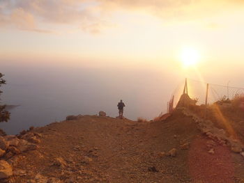 People standing on mountain against sky during sunset