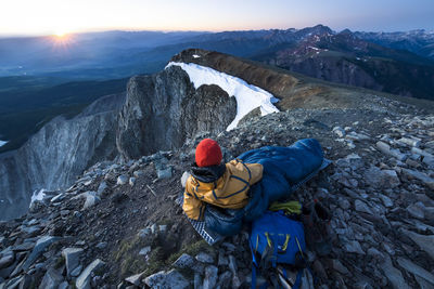 Male hiker relaxing in sleeping bag on mountain during winter