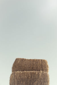 Close-up of hay bales on field against clear sky