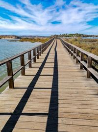 View of footpath leading towards sea against sky