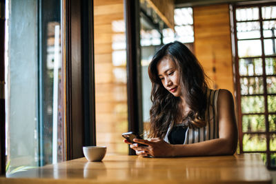 Young woman looking through smart phone on table