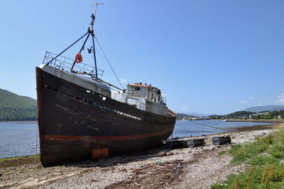 Ship moored on beach against clear sky