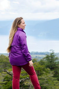 Rear view of woman standing on field against mountains