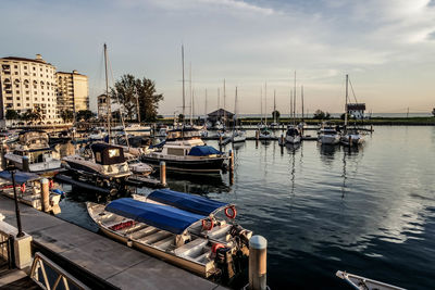 Boats moored at harbor against sky