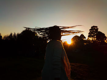 Rear view of silhouette woman standing against orange sky