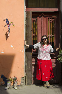 Full length portrait of woman standing against building