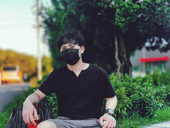 Full length of young man sitting outdoors