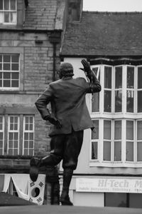 Rear view of man walking against building in city