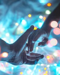 Close-up of hand on illuminated light at night