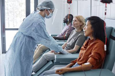 Woman donating blood talking with nurse wearing face shield in clinic