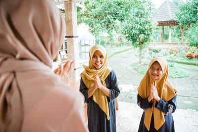 Mother and daughter greeting with lady outside home