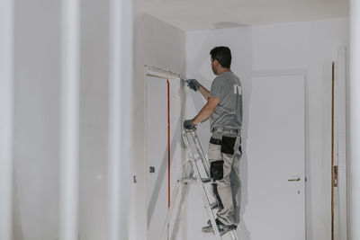 A young builder is plastering a doorway.