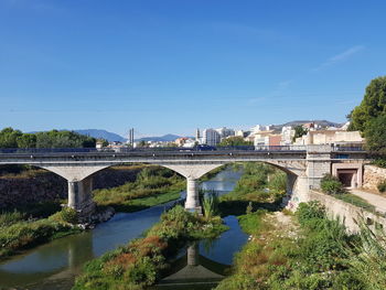 Arch bridge over river against blue sky