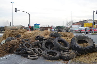 Obsolete tires at junkyard by road against sky