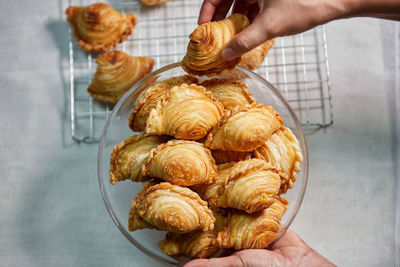 Hand holding curry puff in a glass bowl