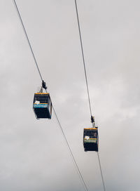 Low angle view of overhead cable car against sky