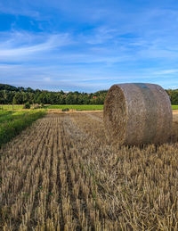 Hay bales on field against sky