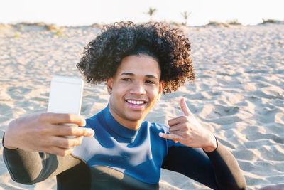 Portrait of smiling young woman using smart phone at beach