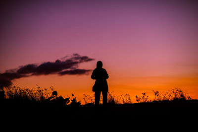 Silhouette people standing on field against sky during sunset