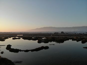 Scenic view of lake against clear sky during sunset