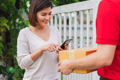 Midsection of woman holding mobile phone while standing on camera