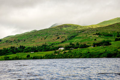 Scenic view of river by mountains against sky