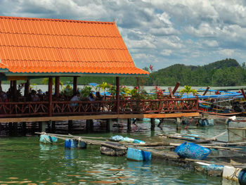Boats moored in water against cloudy sky