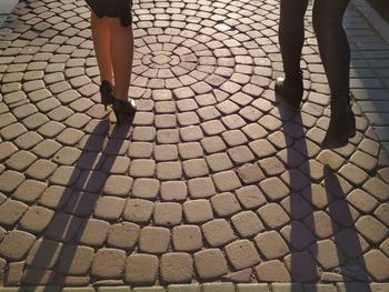 Low section of friends walking on cobbled street