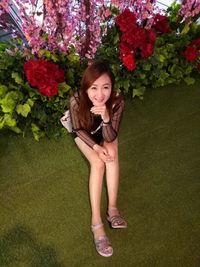 Portrait of smiling young woman sitting by flowers in building