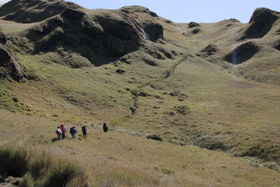 People walking on arid landscape against sky