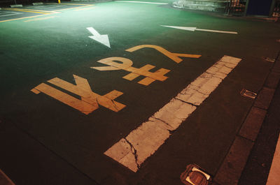High angle view of arrow sign on street at night