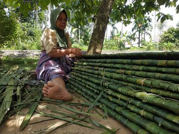 Full length of woman sitting against trees