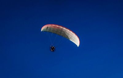 Low angle view of person paragliding against clear blue sky