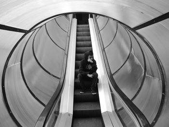 Man sitting on escalator