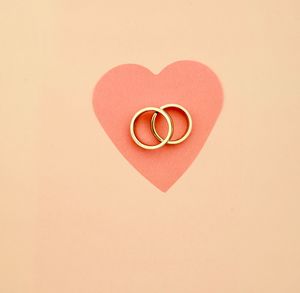 High angle view of wedding rings and heart shape paper on table