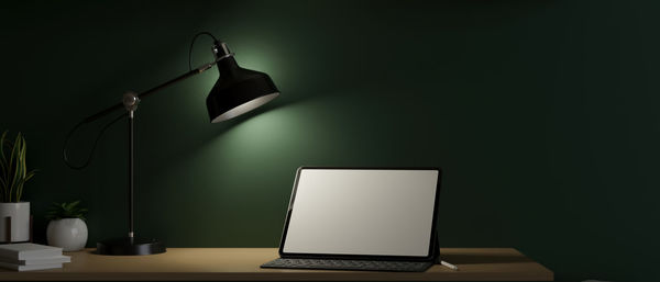 Illuminated electric lamp on table against wall