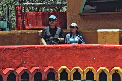 Couple sitting by retaining wall in park