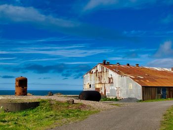 House on field by building against blue sky