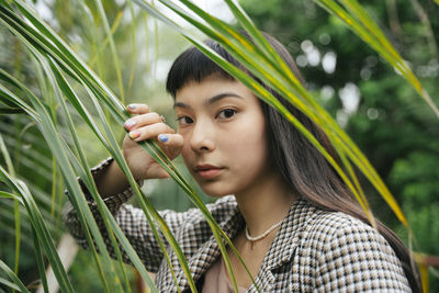 Portrait of young woman standing by tree