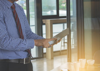 Midsection of man using digital tablet in office