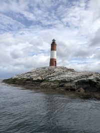 Lighthouse by sea against sky