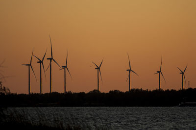 Silhouette cranes against sky during sunset