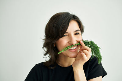 Portrait of young woman holding ice cream against white background