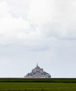 Townscape seen from field against cloudy sky