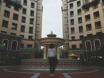 Woman standing in city against sky