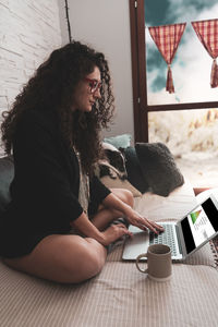 Young woman using mobile phone while sitting at home