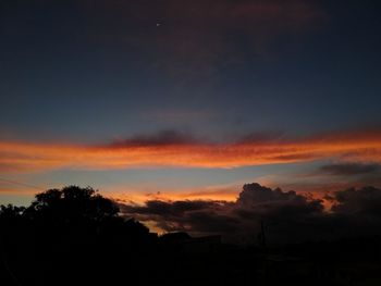 Low angle view of silhouette trees against dramatic sky