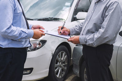 Man holding camera while standing in car