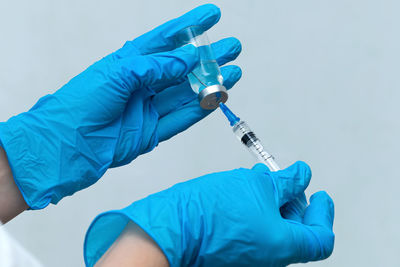 Cropped hands of doctor holding syringe with vial at hospital