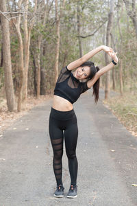 Full length portrait of young woman standing on road